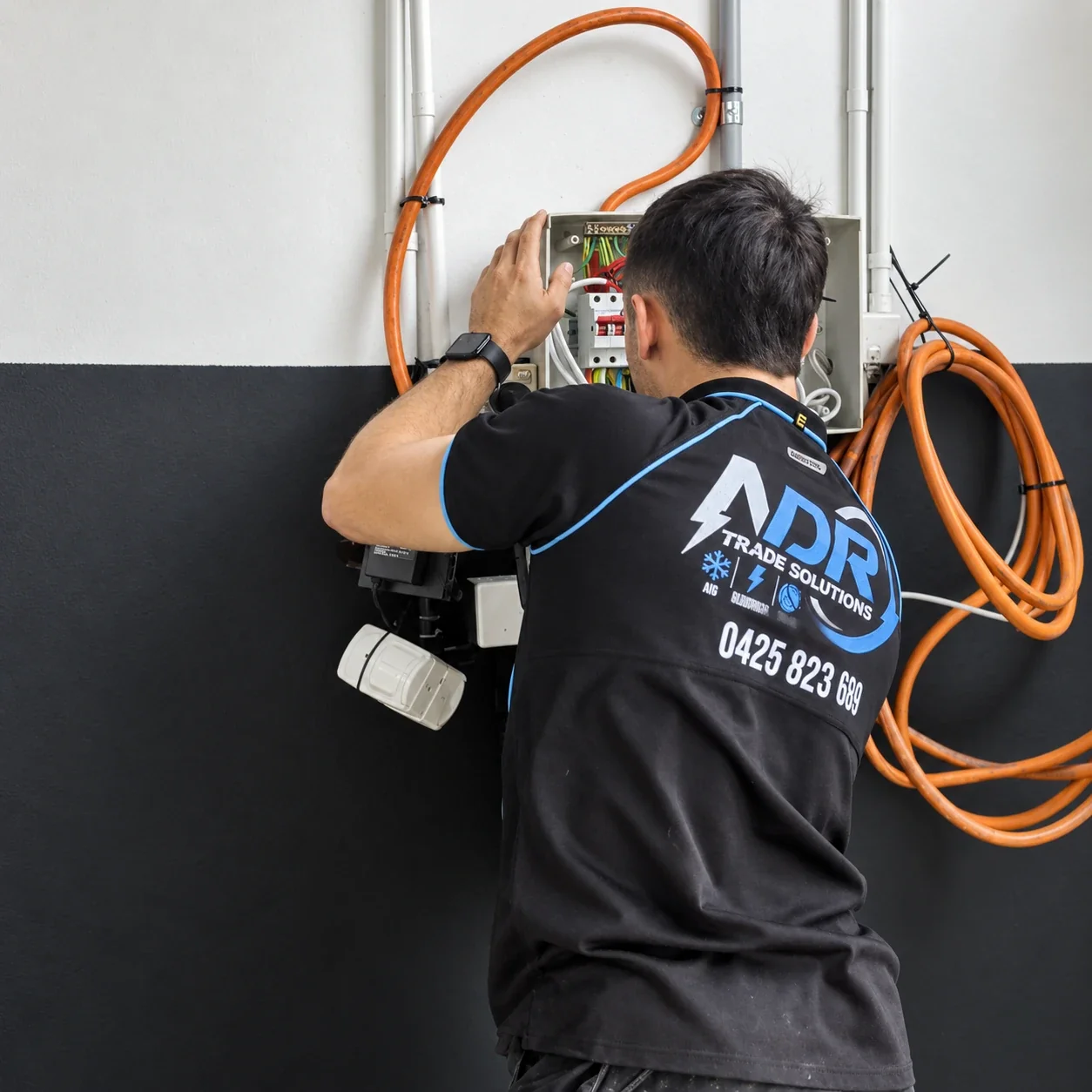 An NDR electrician working at an open electrical board